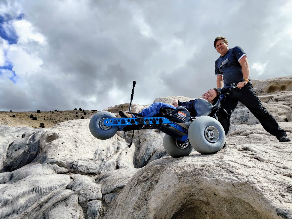 Man with cerebral palsy prepares to descend a steep trail in the Extreme Motus off-road wheelchair