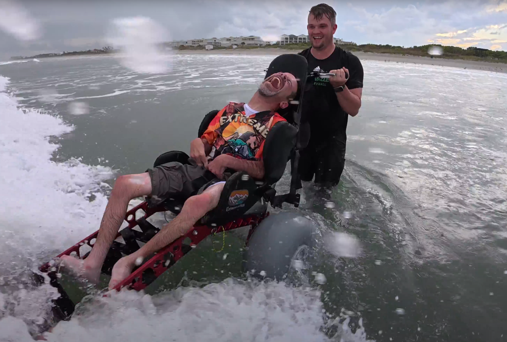 Man in beach wheelchair riding over the waves.