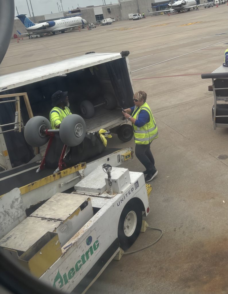 United Airlines ground crew loading Extreme Motus all-terrain wheelchairs with balloon beach tires onto a baggage cart