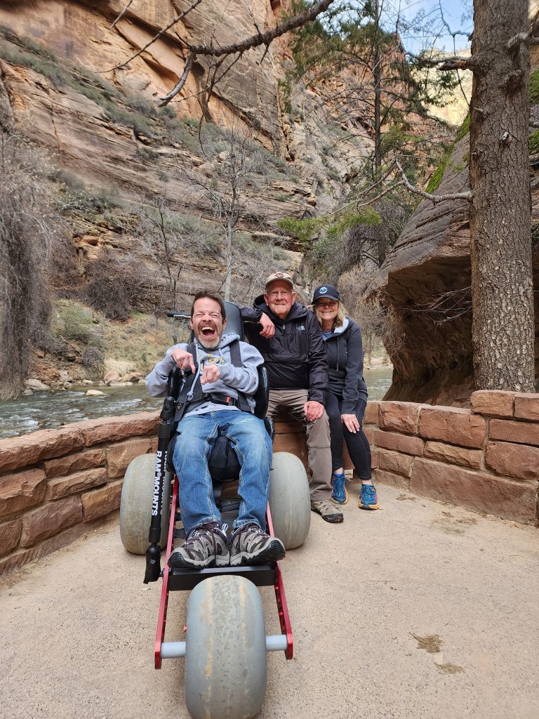 Sam Durst laughing with family beside the river in Zion National Park