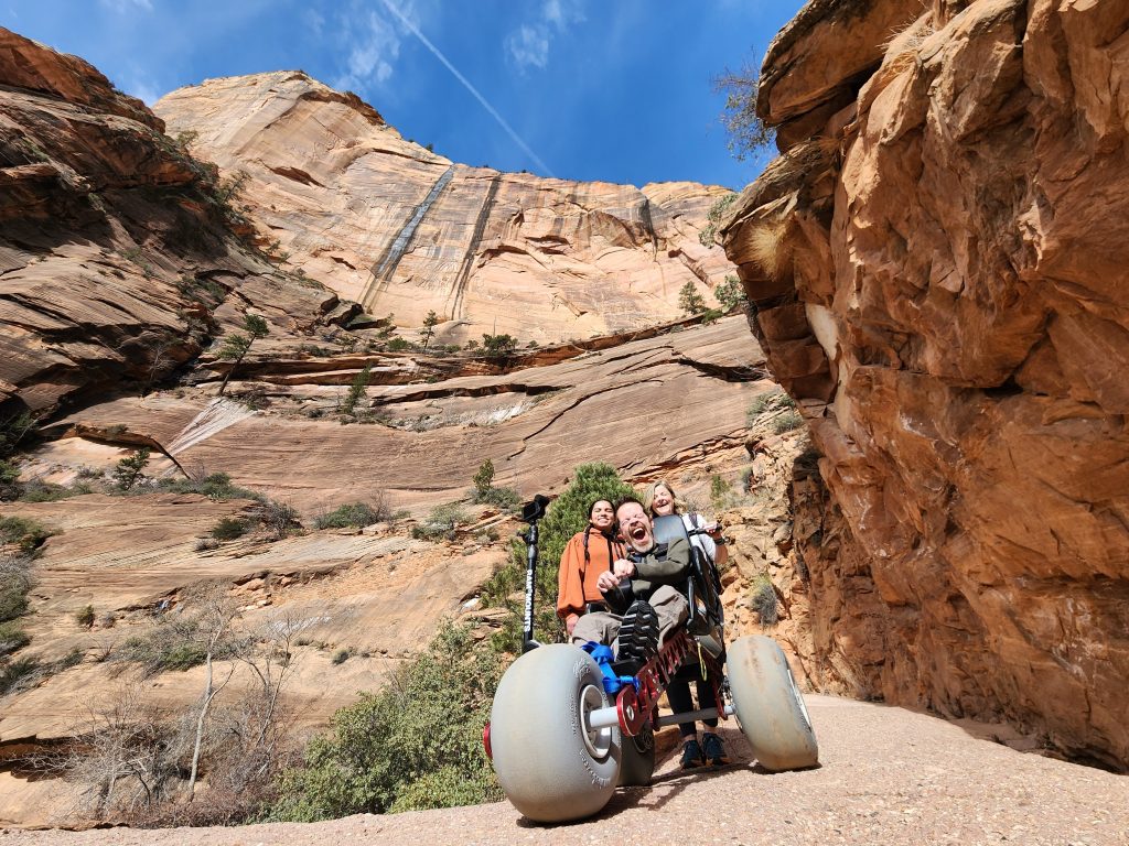 Sam Durst laughing in the Extreme Motus wheelchair against Zion's canyon walls