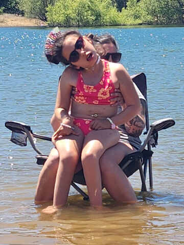 Addisyn celebrating her birthday sitting in the water with her family, made possible by an Extreme Motus all-terrain wheelchair