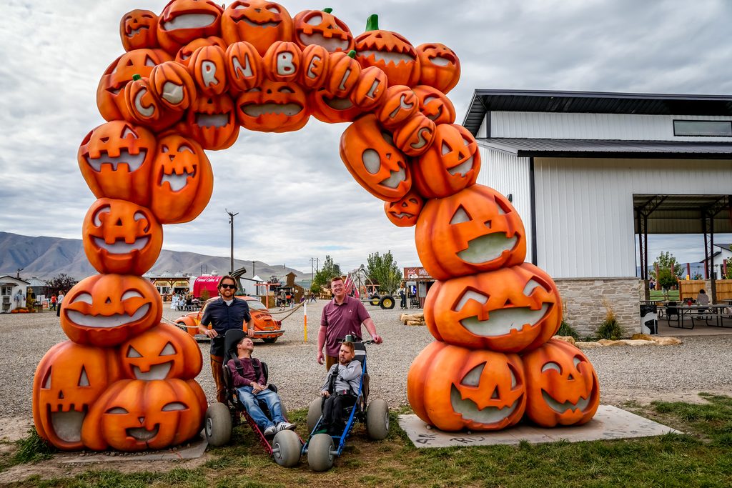 Cornbelly's wheelchair accessible entrance: riders in Extreme Motus all-terrain wheelchairs under the giant jack-o'-lantern arch in Spanish Fork